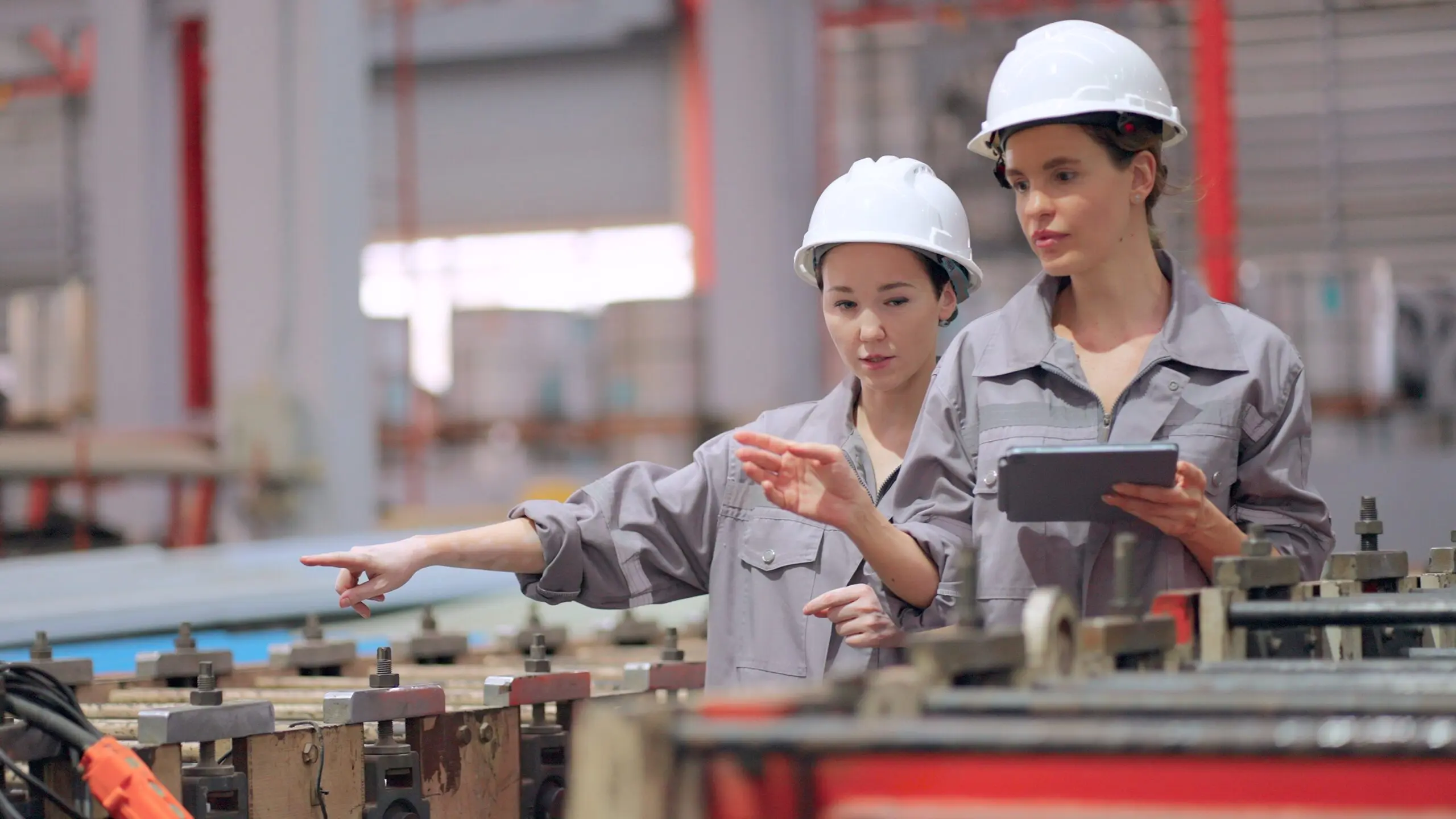 Workers in factory, wearing helmets, discussing