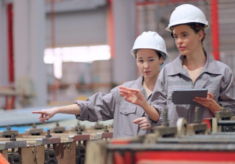 Workers in factory, wearing helmets, discussing